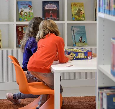 2 Mädchen spielen an einem Tisch in der Kinderbibliothek