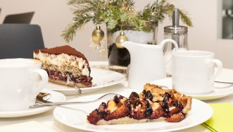 Gedeckter Tisch mit zwei Stück Kuchen auf Tellern, zwei Tassen und weihnachtlicher Tischdeko Quelle: Café Stadtgespräch