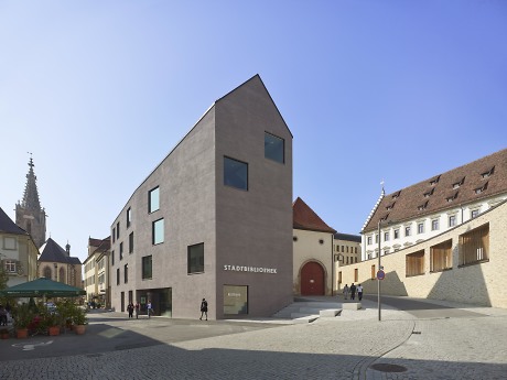 Ansicht eines großen Gebäudes mit grauer Fassade, davor Fußgängerzone mit Passanten Quelle: Roland Halbe