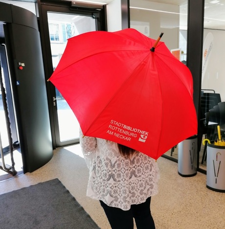 Mensch von hinten, er trägt einen roten Regenschirm Quelle: Stadtbibliothek Rottenburg