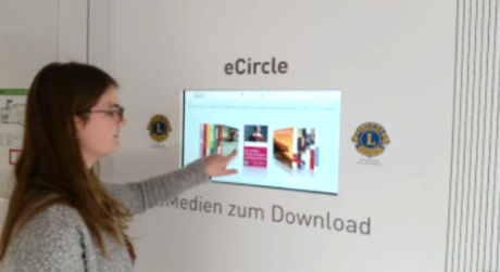 Eine junge Frau steht vor einem Touchscreen, der in der Wand installiert ist. Sie tippt auf den Bildschirm Quelle: Stadtbibliothek Rottenburg am Neckar