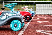 Drei nebeneinander stehende Bobbycars auf einer Rennbahn
